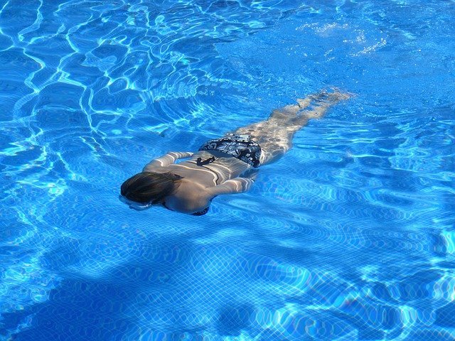 Woman Swimming Underwater In Pool